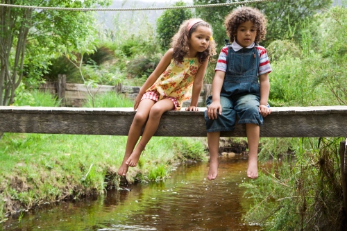 Girl and boy on footbridge over stream