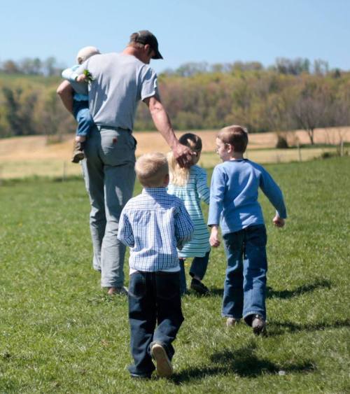 children with farmer in meadow
